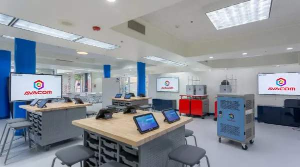STEAM classroom with AVACOM interactive displays, wooden workbenches with tablets on stands and a device charging cart